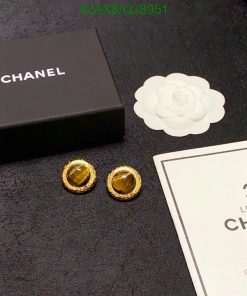 Chanel earrings and packaging on dark surface.
