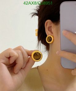 Person showcasing yellow earrings while holding a phone.