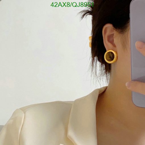 Person wearing golden circular earrings with phone