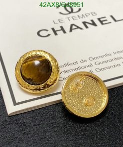 Gold designer button earrings on certificate background.