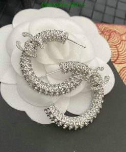 Sparkling hoop earrings with diamond-like stones on white flower.