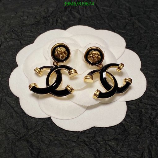 Black and gold designer earrings on white petal-like background.