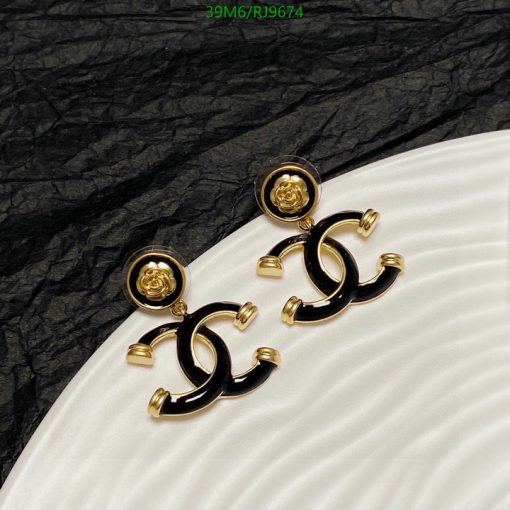 Elegant black and gold designer earrings on textured background.