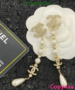 Chanel pearl drop earrings on textured surface.