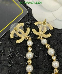 Gold pearl drop earrings on black texture.