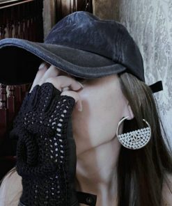 Person posing with hat, earring, and fingerless glove.