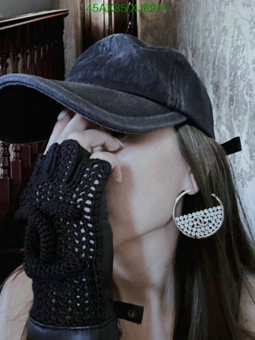 Person posing with hat, earring, and fingerless glove.