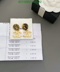 Gold-tone branded earrings on invoice beside jewelry box.