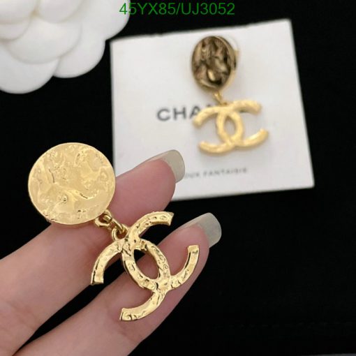 Gold designer logo earrings held by fingers.