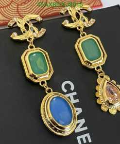 Gold designer earrings with colored gemstones on display.