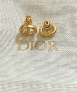 Gold Dior logo cufflinks on white fabric.