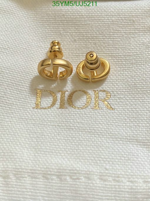 Gold Dior logo cufflinks on white fabric.