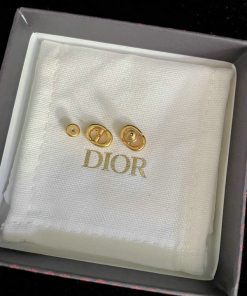 Gold Dior cufflinks on white fabric in box.