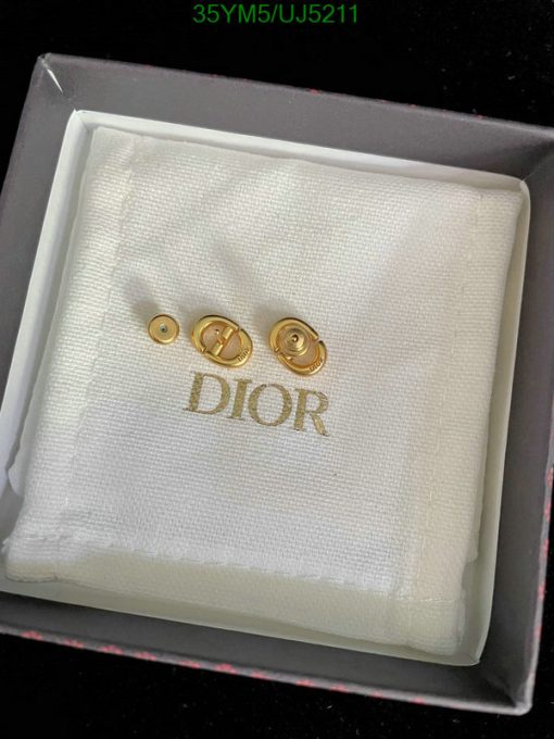 Gold Dior cufflinks on white fabric in box.