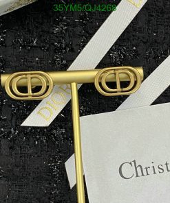 Gold Dior logo pin with packaging materials.