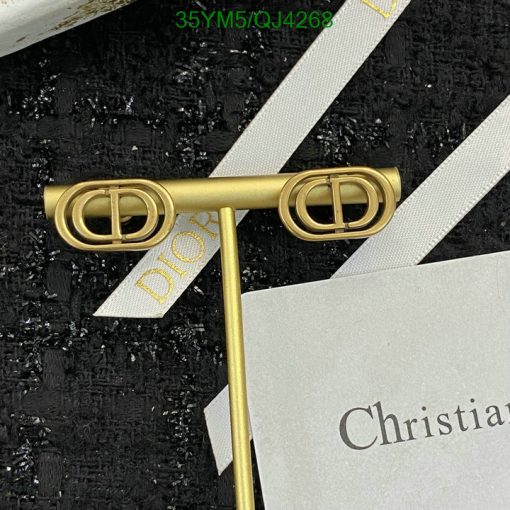 Gold Dior logo pin with packaging materials.