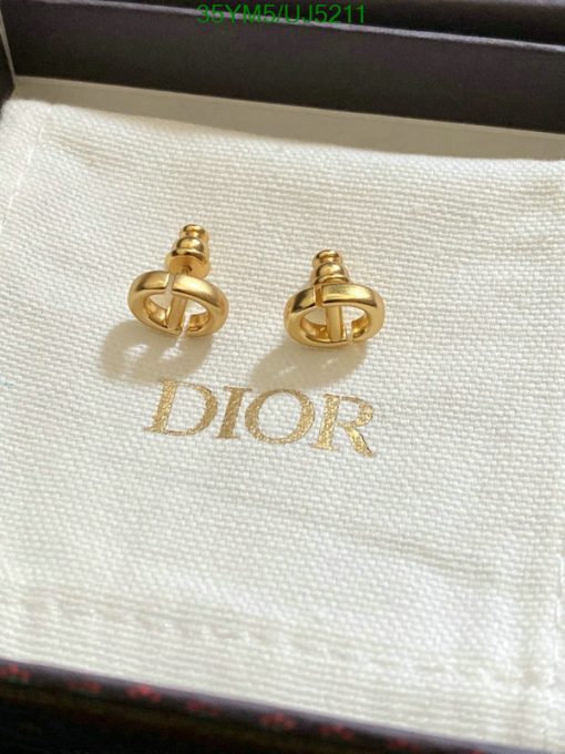 Gold designer logo earrings on branded display fabric.