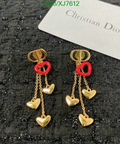 Designer heart-shaped dangle earrings on textured background.