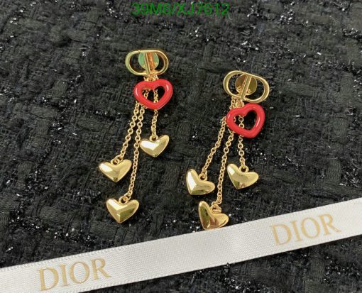 Gold heart-shaped Dior earrings on black textured background.