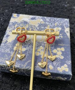 Gold heart dangling earrings on floral patterned box.