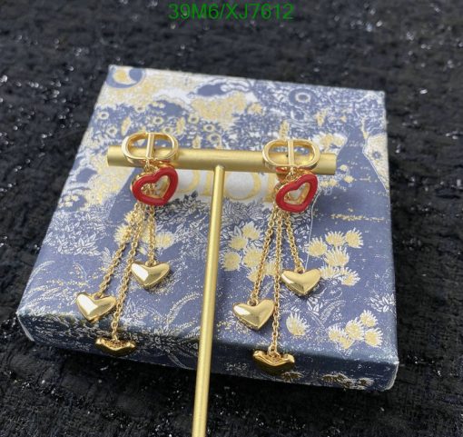 Gold heart dangling earrings on floral patterned box.