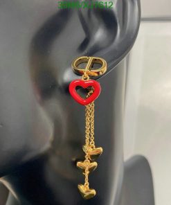 Red heart earring with gold chain on mannequin ear.