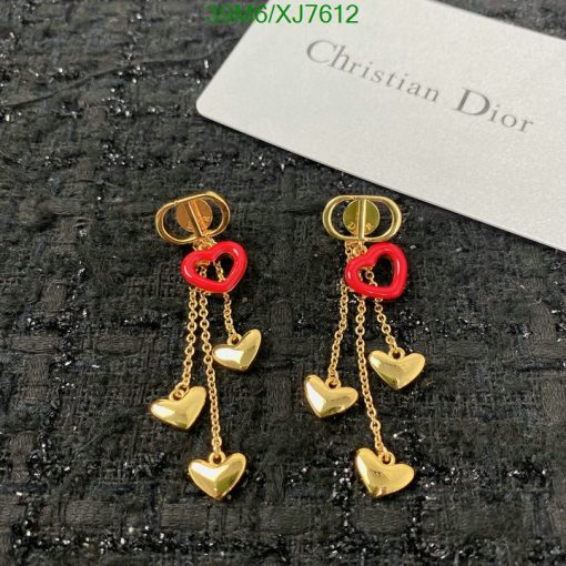 Gold heart charm earrings with red accents on fabric.