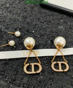 Pearl Dior logo earrings on textured fabric.