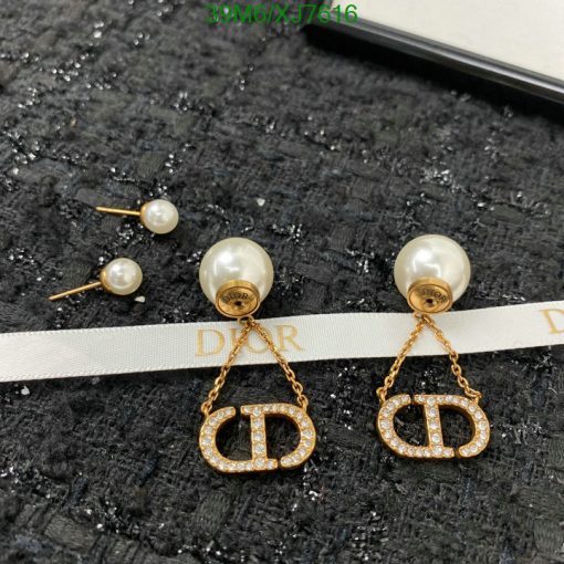 Pearl Dior logo earrings on textured fabric.