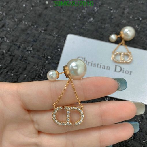 Gold pearl earrings with designer logo on packaging.