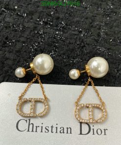 Pearl earrings with gold Dior logo on black background.