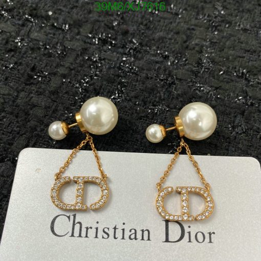 Pearl earrings with gold Dior logo on black background.