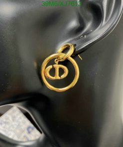 Gold designer logo earring on black mannequin ear.