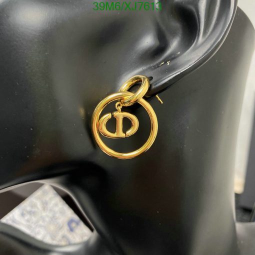 Gold designer logo earring on black mannequin ear.