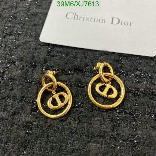 Designer gold-tone logo earrings on textured surface.