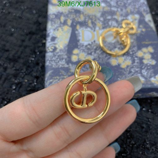 Gold designer logo earrings with box in background.