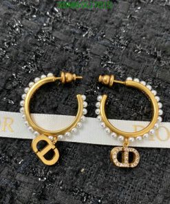 Pearl-studded gold hoop earrings on textured background.