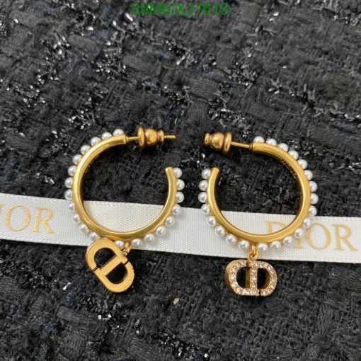 Pearl-studded gold hoop earrings on textured background.