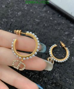 Gold pearl hoop earrings in hand.