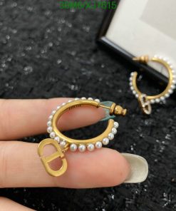 Gold pearl hoop earrings on black surface.