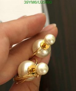 Hand holding pearl gold earrings.