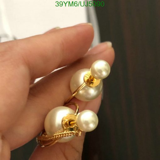 Hand holding pearl gold earrings.