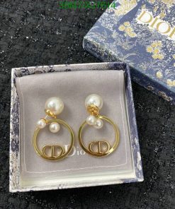 Pearl earrings in Dior box on black texture.