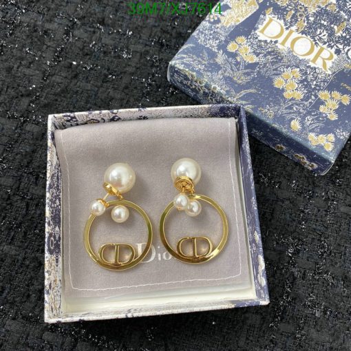 Pearl earrings in Dior box on black texture.