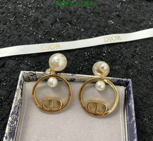 Dior pearl earrings with gold logo detail on black surface.