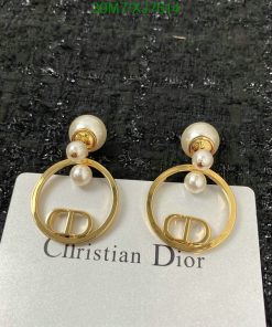 Gold pearl designer earrings on textured background.