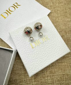 Dior branded earrings on textured white display.