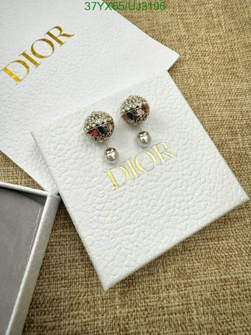 Dior branded earrings on textured white display.