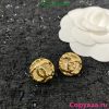 Gold rose-shaped earrings on textured background.