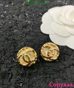 Gold rose-shaped earrings on textured background.